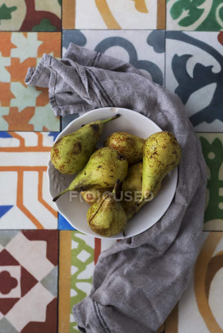 Tigela de peras maduras na superfície ornamental amarrada com pano — Fotografia de Stock