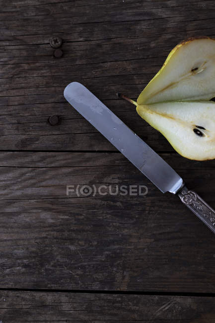 Coltello e pera fresca matura dimezzata su tavolo in legno — Foto stock