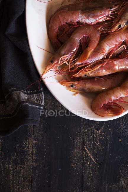 From above plate with tasty boiled shrimps placed on aged tabletop near napkin — Stock Photo