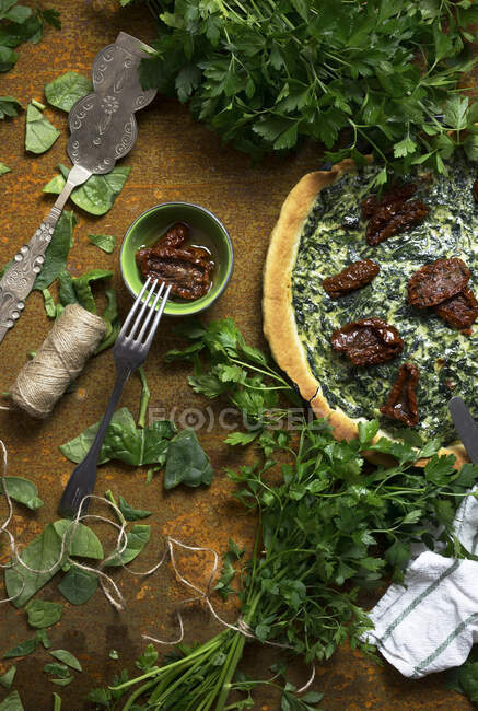 From above bunches of fresh parsley and yummy vegetarian dish placed on shabby tabletop near cutlery — Stock Photo