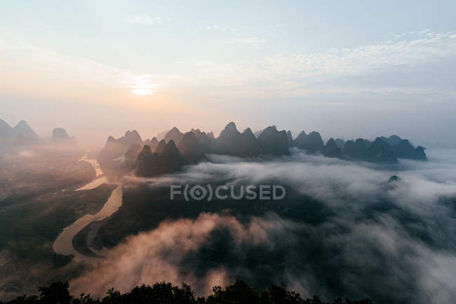 Таинственный речной пейзаж среди высоких гор в тумане — стоковое фото