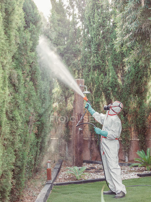 Fumigador em substância pulverizadora uniforme branca no jardim — Fotografia de Stock