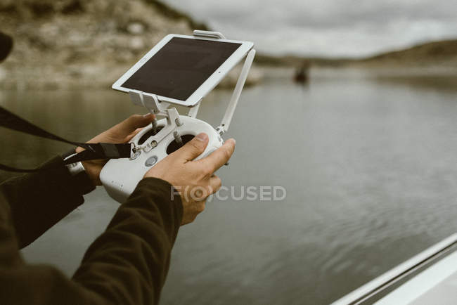 Mãos de turista usando controlador com tablet em stand enquanto navega em barco na água em dia nublado — Fotografia de Stock