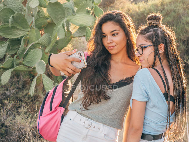 Усміхнені модні молоді жінки беруть селфі в сільській місцевості — стокове фото