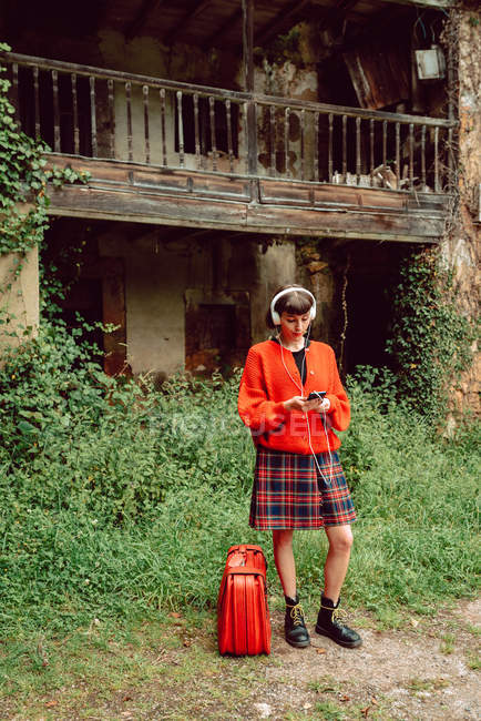 Donna in cuffia con valigia ad ascoltare musica in campagna — Foto stock