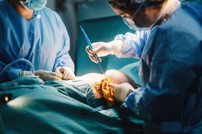 Cirurgião médico irreconhecível fazendo cirurgia com instrumentos e enfermeira de colheita — Fotografia de Stock