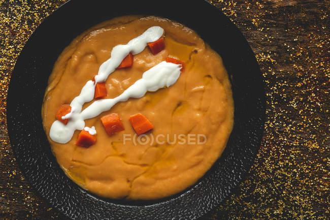 From above tasty fragrant vegetable cream soup with cut ripe carrot on wooden background — Stock Photo