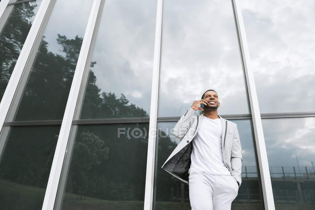 Eleganter schwarzer Mann spricht Smartphone schiefes Gebäude — Stockfoto