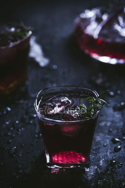 Carafe and crystal glasses with ice filled with red wine on black table — Stock Photo