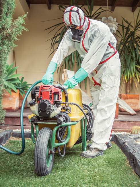 Fumigator pulling treatment hose from machine in yard — Stock Photo