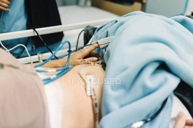 Зверху врожаю жінка лежить на ліжку з датчиком пальця після операції і медсестра стоїть поруч в лікарні — стокове фото