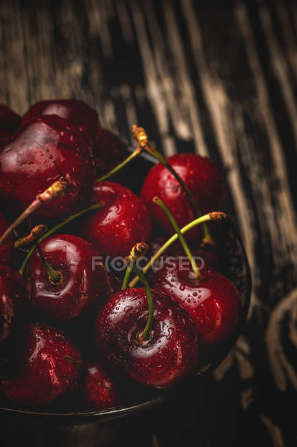 Tasty appetizing ripe washed cherries in bowl on dark wooden table — Stock Photo