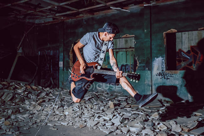 Музикант грає на електрогітарі в покинутому місці — стокове фото