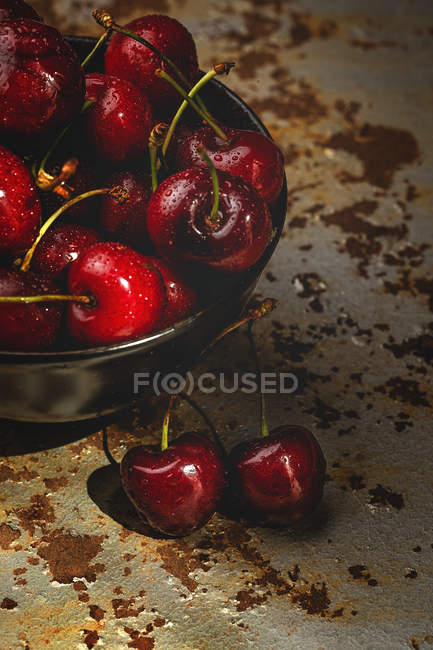 Tasty appetizing ripe cherries in bowl on rusty table — Stock Photo