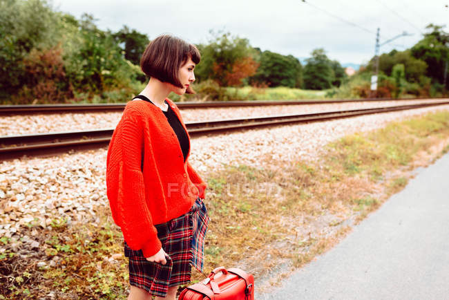 Giovane donna in piedi alla stazione ferroviaria in campagna — Foto stock