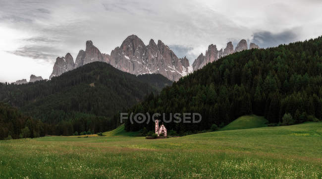Malerische Kirche auf einem grünen Hügel mit felsigen Bergen im Hintergrund — Stockfoto