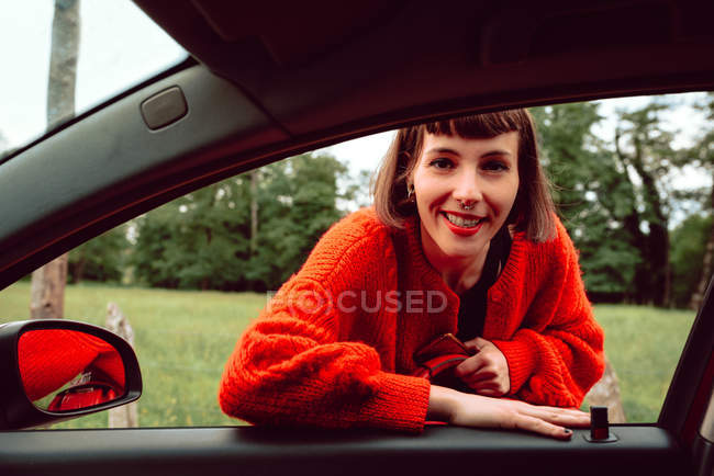 Jovem mulher de pé na janela da frente do carro — Fotografia de Stock
