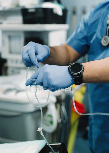 Colheita de mãos masculinas em luvas de borracha azul preparando remédio para infusão no hospital em fundo embaçado — Fotografia de Stock