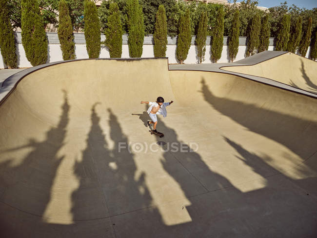 Von oben glücklicher kleiner Junge mit Schutzhelm und Skateboard auf Rampe im Skatepark — Stockfoto