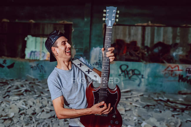 Un musicien joue de la guitare électrique dans un endroit abandonné — Photo de stock