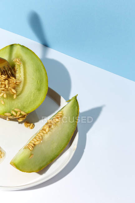 Taglio maturo appetitoso dolce melone snocciolato su piatto su fondo blu — Foto stock