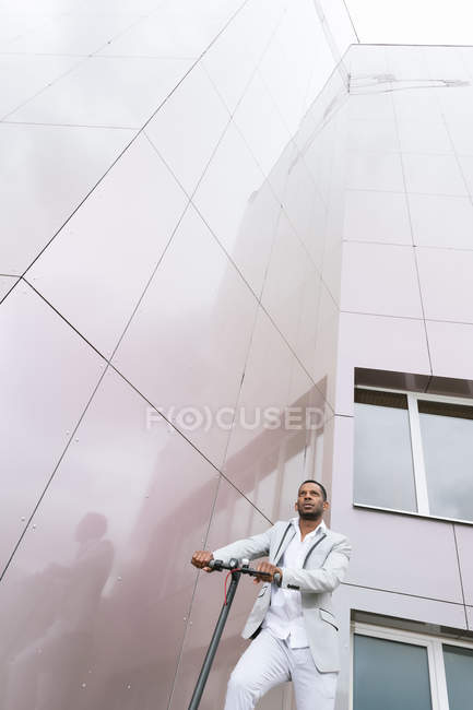 Black man in suit on electric scooter in business center — Stock Photo