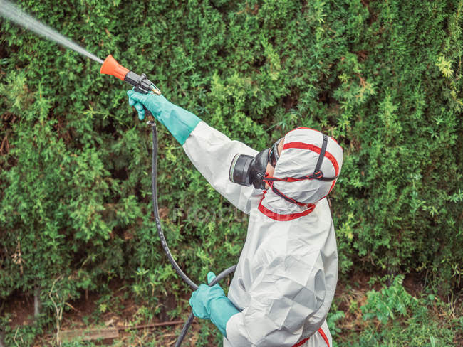 Fumigador em substância pulverizadora uniforme branca no jardim — Fotografia de Stock