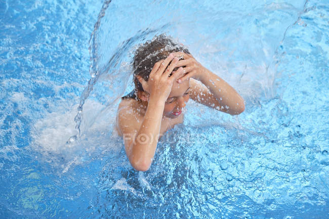 Дитяче гальмування для повітря із закритими очима та відкритим ротом під водоспадом у аквапарку — стокове фото