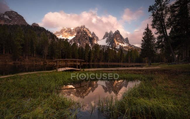 Landschaft mit rundem Teich auf sattgrünem Rasen, der Himmel und Berge in den Dolomiten reflektiert, — Stockfoto