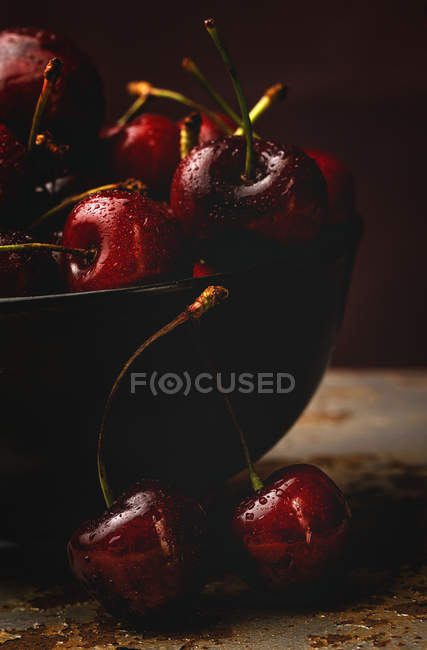Tasty appetizing ripe cherries in bowl on dark background — Stock Photo
