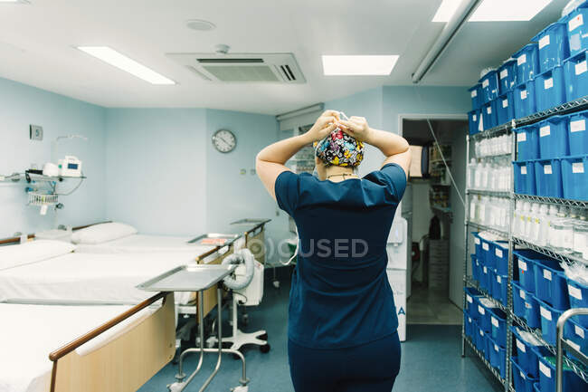 Back view of medic in blue hospital uniform standing and getting ready for surgery in clinic corridor — Stock Photo