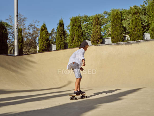 Von oben glücklicher kleiner Junge mit Schutzhelm und Skateboard auf Rampe im Skatepark — Stockfoto