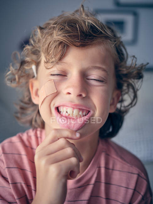Unsteady baby tooth in wide open mouth of anonymous child pulling lip down to show tooth with closed eyes — Stock Photo