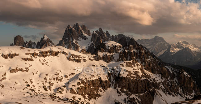 Picos afiados de montanhas rochosas contra céu nublado em susnet — Fotografia de Stock