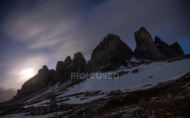 Montañas oscuras en llanura blanca bajo cielo estrellado - foto de stock