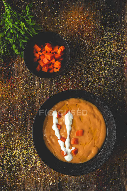 З зверху смачний ароматичний кремовий суп з достиглим морквою і петрушкою на дерев'яному тлі. — стокове фото