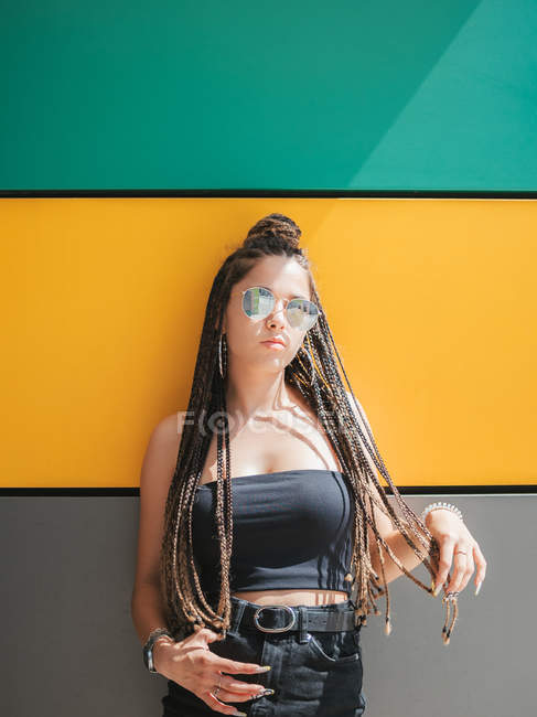 Pretty stylish teenage girl with unique dreadlocks looking at camera on colorful background — Stock Photo