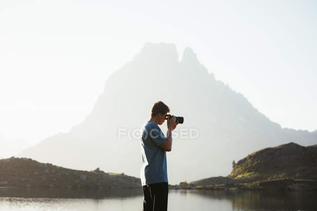 Hombre tomando fotos de paisaje de montaña - foto de stock