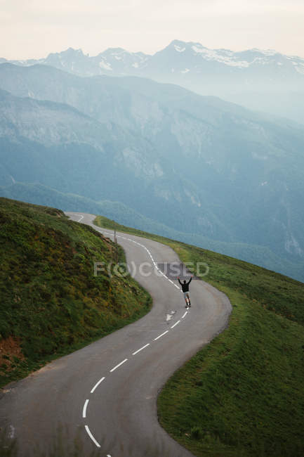 Vue panoramique sur les montagnes et skateboard homme sur la route — Photo de stock