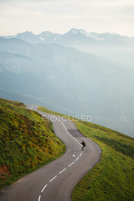 Vista panoramica sulle montagne e skateboard uomo su strada — Foto stock
