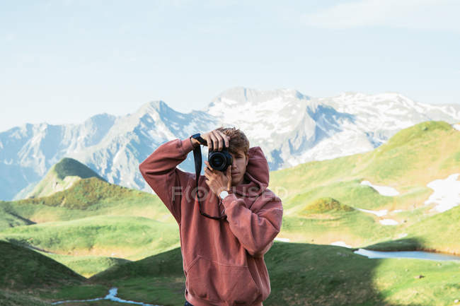 Man taking photo in mountain landscape — Stock Photo