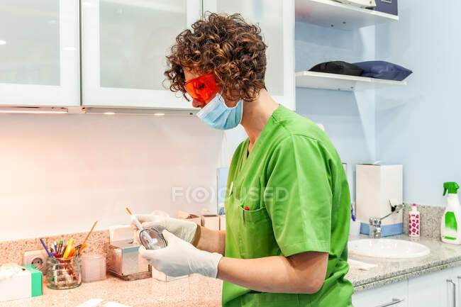 Dentiste en uniforme et seringue de remplissage de masque — Photo de stock
