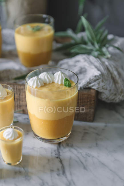 Gros plan de savoureuse mousse de mangue aromatique dans des verres sur plateau de marbre blanc — Photo de stock