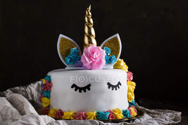Bonito pastel de unicornio con ojos cerrados pintados en tela sobre fondo negro - foto de stock