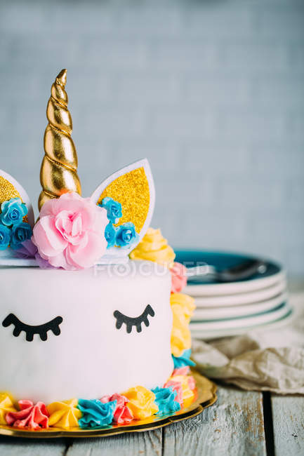 Симпатичний єдиноріг торт з розфарбованими закритими очима на дерев'яному столі — стокове фото