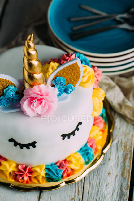 Cute unicorn cake with painted closed eyes on wooden table — Stock Photo
