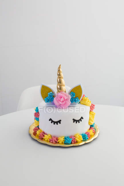 Симпатичний єдиноріг торт з розфарбованими закритими очима на білому столі — стокове фото