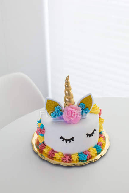 Mignon gâteau licorne avec les yeux fermés peints sur la table blanche — Photo de stock