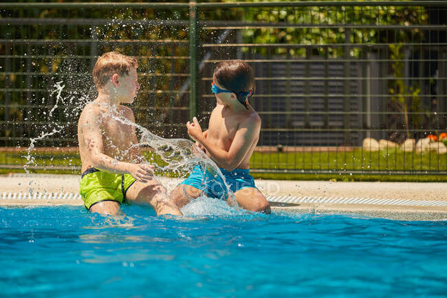 Espalhando crianças felizes na borda da piscina se divertindo e jogando juntos em dia ensolarado brilhante — Fotografia de Stock