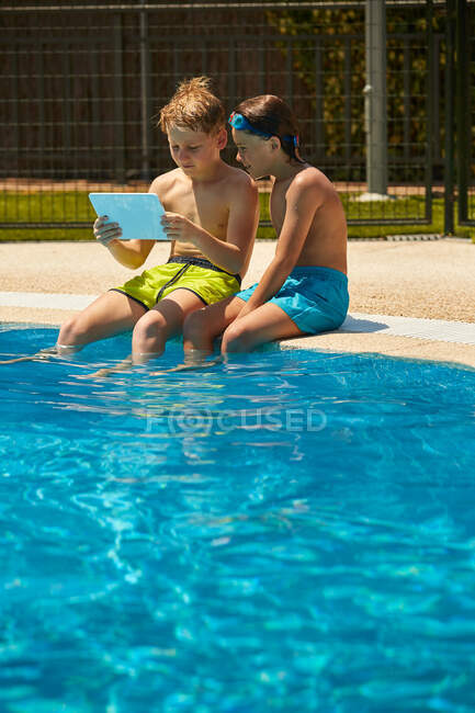 Garçons sur tablette de navigation côté piscine — Photo de stock
